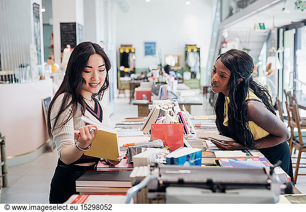 Junge Geschäftsfrauen stöbern in Buchhandlung