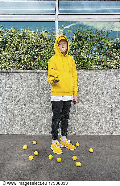 Junge hält Gummiente und steht inmitten von Zitronen