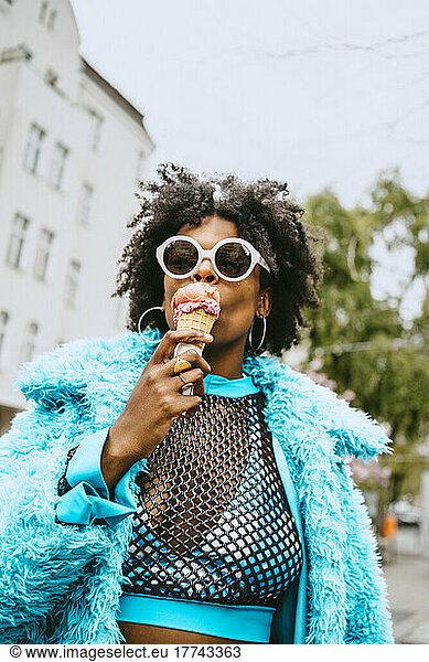 Junge Hipster-Frau mit Pelzjacke isst Eiscreme
