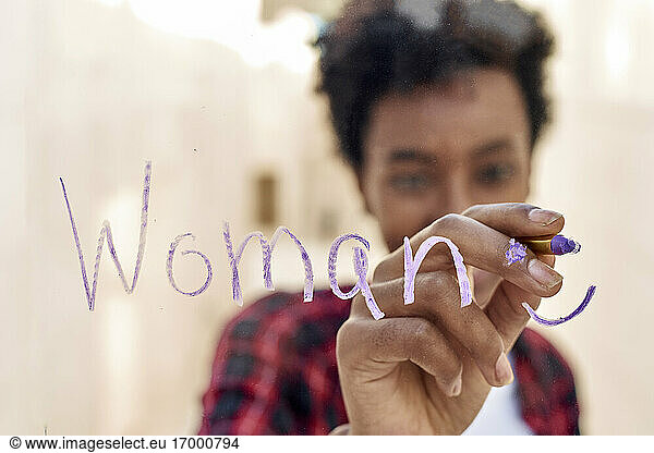 Junge Hipsterin schreibt WOMAN  während sie den Frauentag feiert