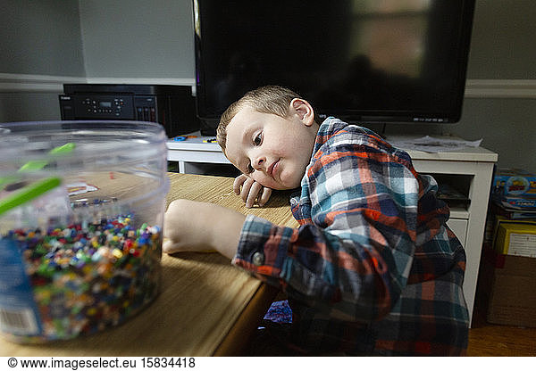 Junge im Vorschulalter legt bei Bastelprojekt still den Kopf auf den Tisch
