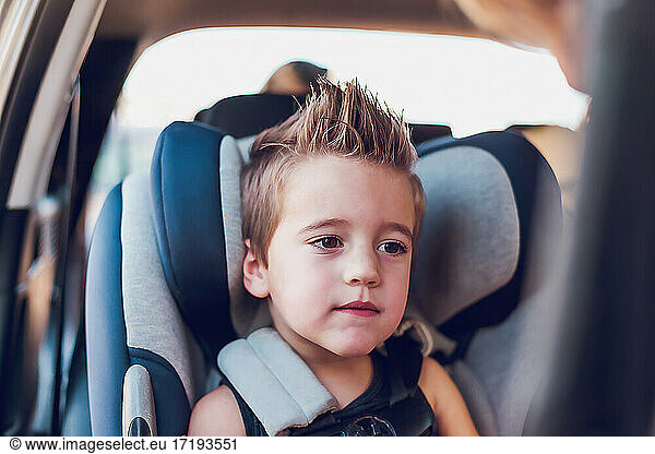 Junge im Vorschulalter sitzt in einem Autositz in einem Auto.