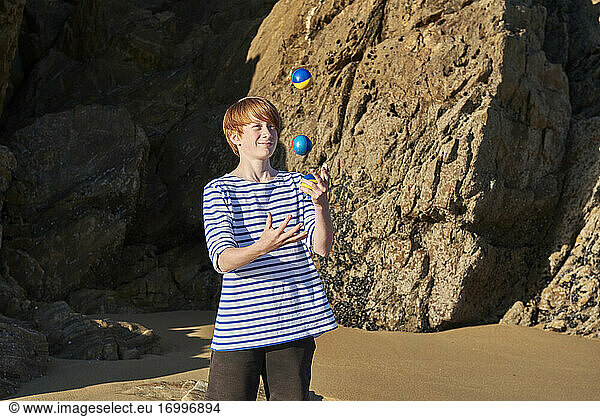 Junge jongliert Bälle beim Spielen am Strand
