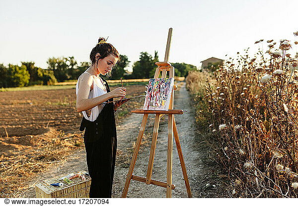 Junge Künstlerin malt auf Staffelei