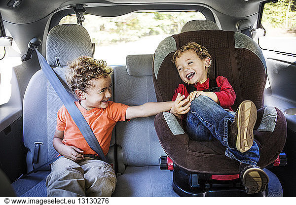 Junge kitzelt Bruder beim Sitzen im Auto
