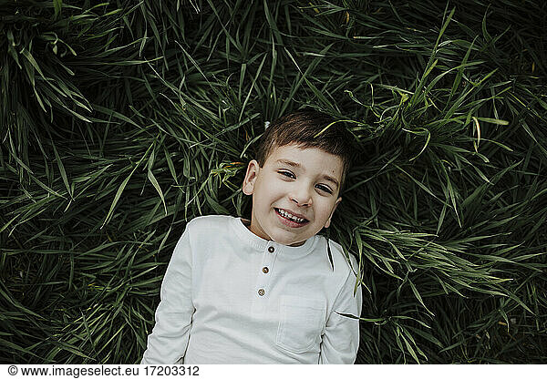 Junge lächelnd im Gras liegend