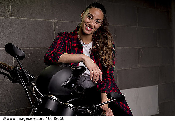 Junge lächelnde Frau auf einem Motorrad sitzend