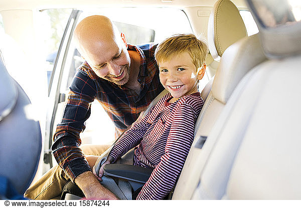 Junge lächelt  als sein Vater den Sicherheitsgurt anlegt