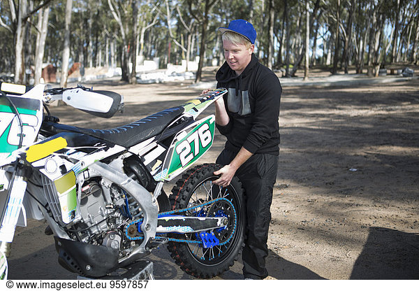 Junge männliche Motocross-Fahrer beim Heben von Motorrädern im Wald