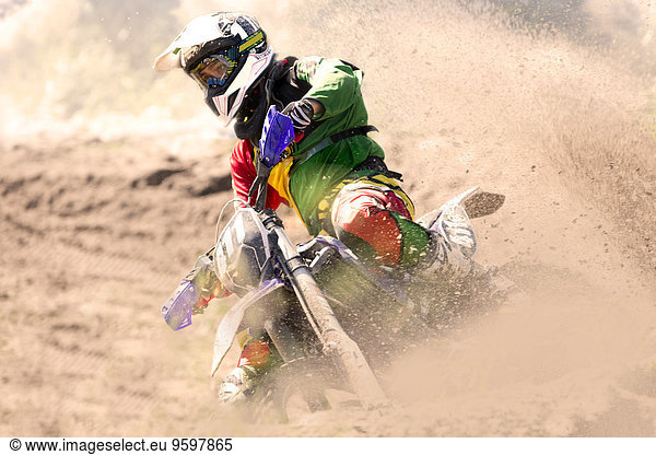 Junge männliche Motocross-Fahrer  die sich in die Schlammbahn lehnen.