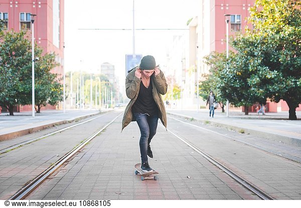 Junge männliche Skateboarder beim Skateboarden auf der Strassenbahn