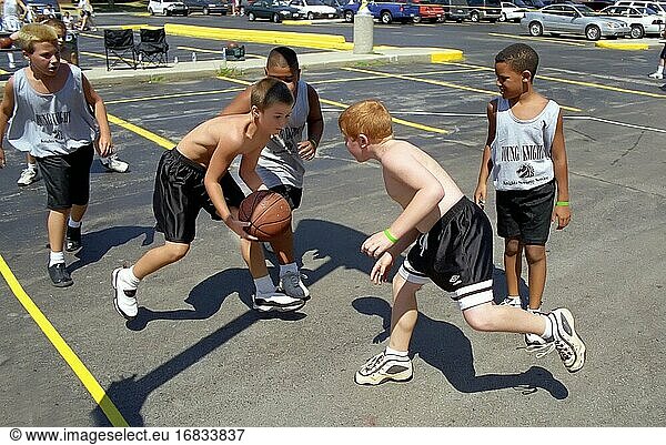 Junge männliche Teilnehmer spielen 3 gegen 3 Basketball im Freien.