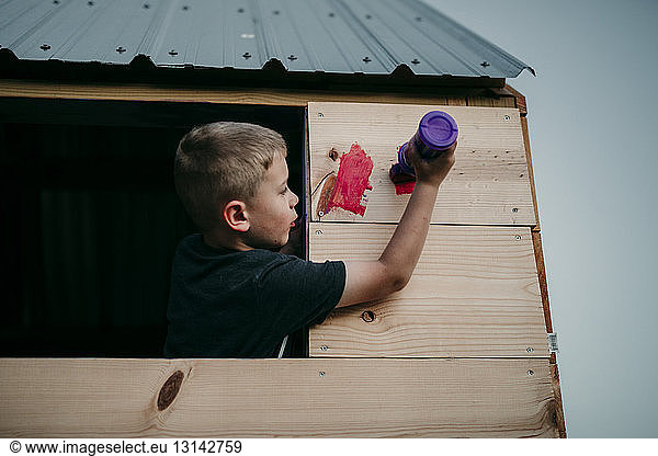 Junge malt Spielhaus