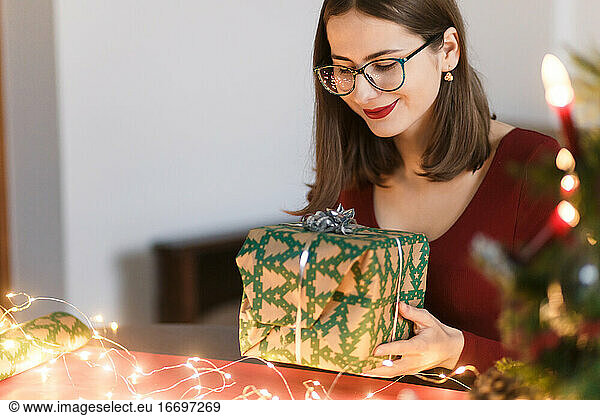 junge Millennial-Frau mit Weihnachtsgeschenken in festlicher Atmosphäre