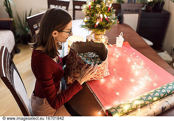 junge Millennial-Frau mit Weihnachtsgeschenken in festlicher Atmosphäre