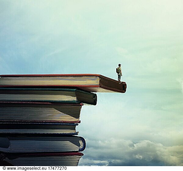 Junge mit einer Tasche auf dem Rücken stehen auf einem Stapel von Büchern Blick weit auf den Horizont. Auf der Suche nach Wissen Konzept
