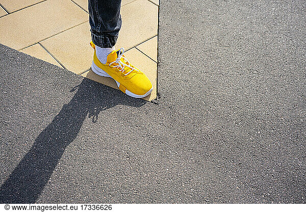 Junge mit gelbem Schuh  der auf einem Fußweg steht
