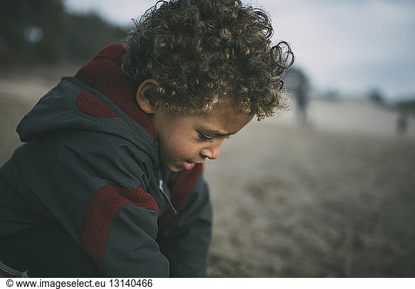 Junge mit Jacke beim Spielen am Strand