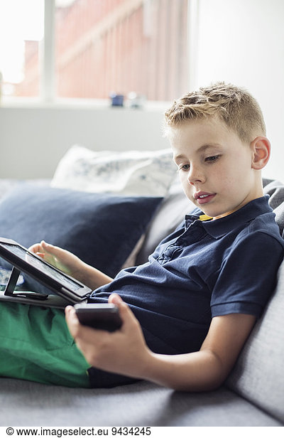 Junge mit Technologien auf dem Sofa zu Hause