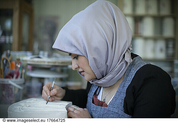 Junge muslimische Künstlerin bei der Arbeit im Kunstatelier