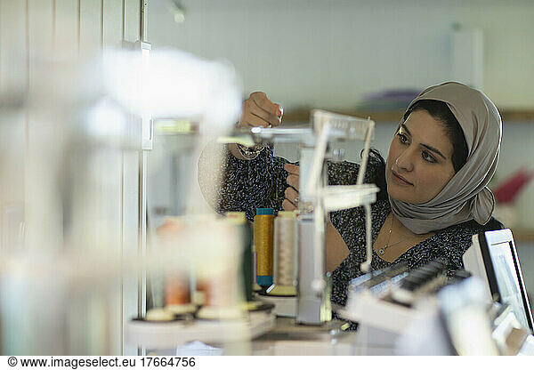 Junge muslimische Näherin bei der Vorbereitung von Garnspulen