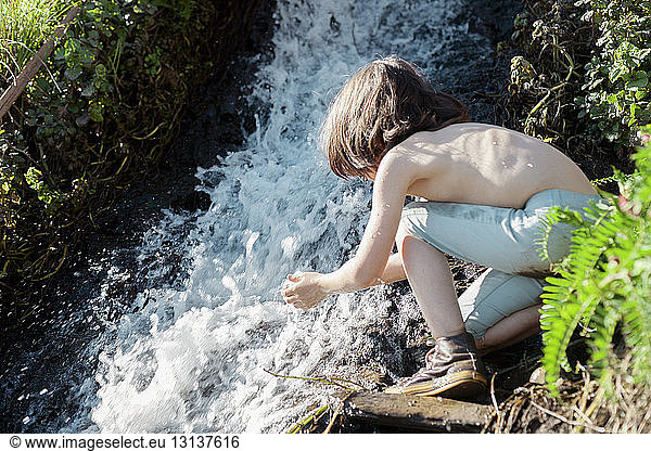 Junge ohne Hemd spielt am Wasserfall