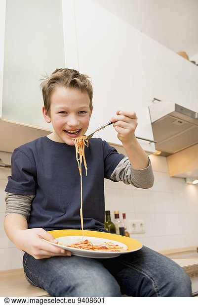 Junge - Person Küche Spaghetti essen essend isst Tresen