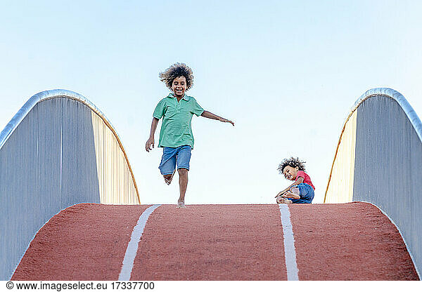 Junge rennt  während sein Bruder von einer Brücke fällt