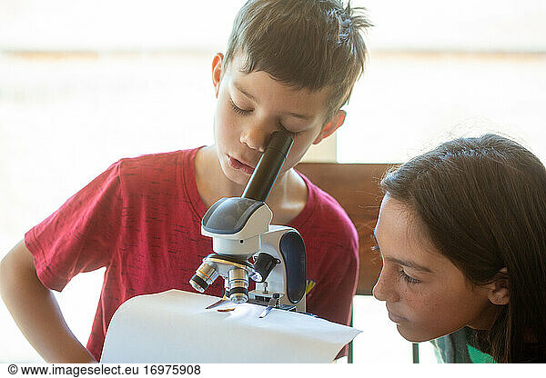 Junge schaut in ein Mikroskop  Mädchen schaut zu