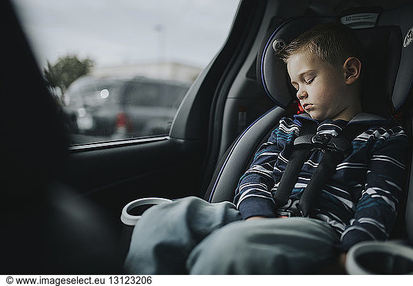 Junge schläft  während er auf einem Autositz sitzt