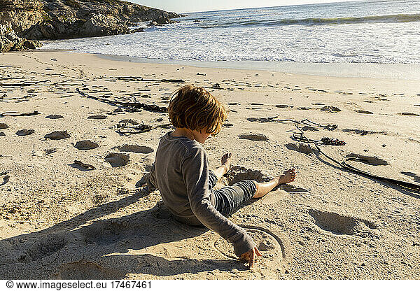 Junge sitzt am Sandstrand