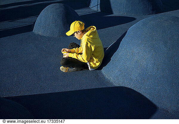 Junge sitzt mit Zitronen im Skateboardpark