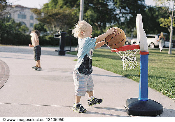 Junge spielt Basketball auf Fußweg