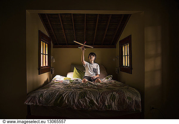 Junge spielt mit Modellflugzeug  während er in der Kabine auf dem Bett sitzt