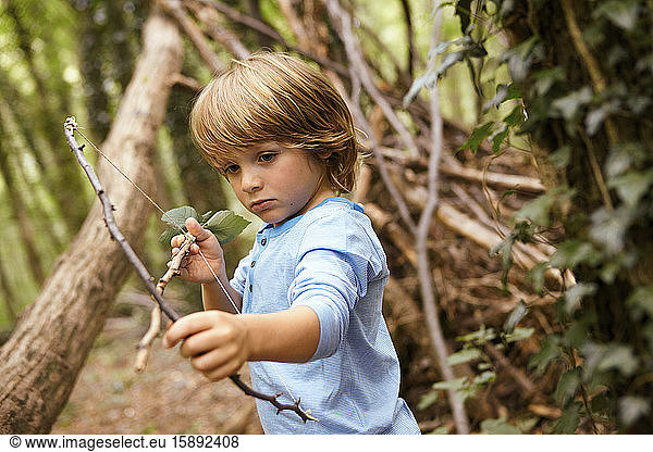 Junge spielt mit Pfeil und Bogen im Wald