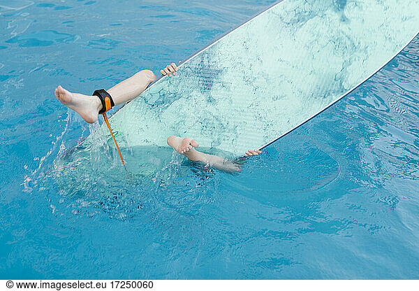 Junge spielt mit Surfbrett im Schwimmbad