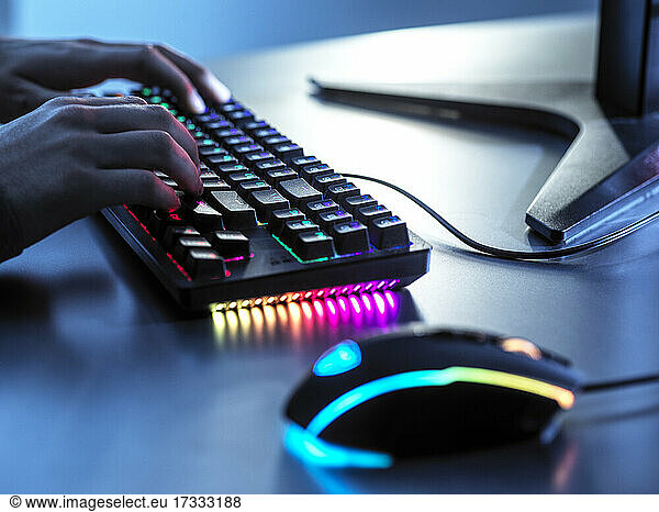 Junge spielt Spiel mit beleuchteter Tastatur auf Tisch
