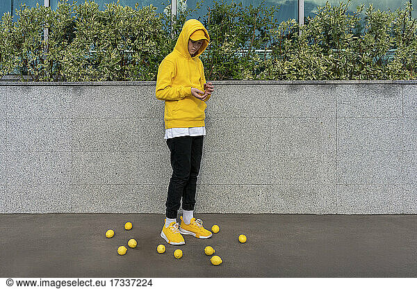 Junge steht inmitten von Zitronen an einer Stützmauer