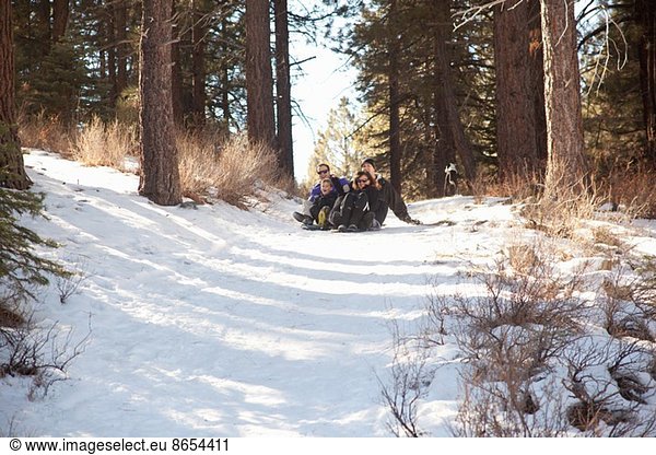 Junge und junge Erwachsene beim Rodeln im verschneiten Wald