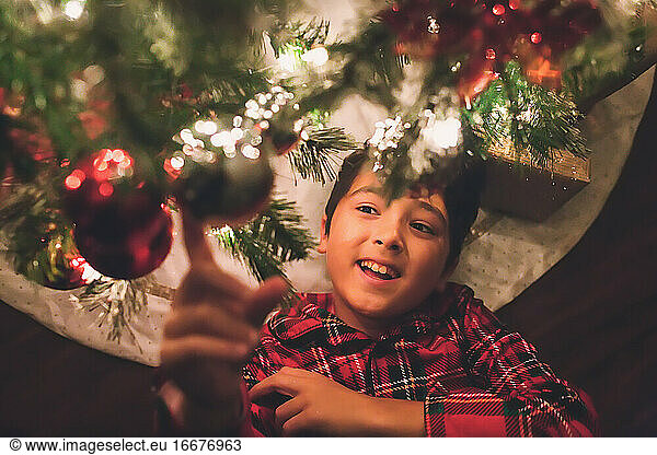 Junge unter dem Weihnachtsbaum bei Nacht