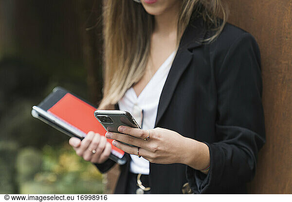 Junge weibliche Berufstätige senden Textnachrichten über ihr Smartphone