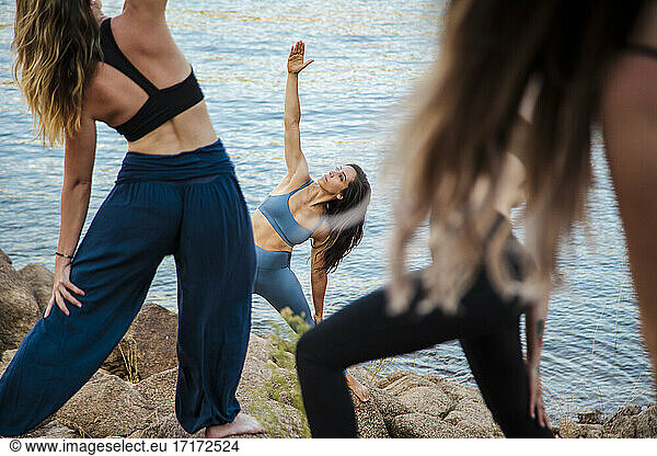 Junge Yogalehrerin unterrichtet Frauen in Dehnübungen