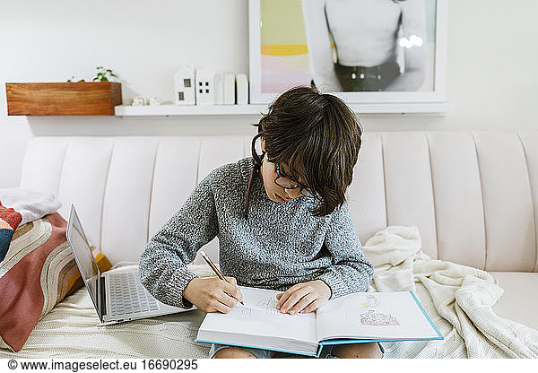 Junge zeichnet auf Notebook auf Sofa zu Hause durch Laptop mit Anweisungen