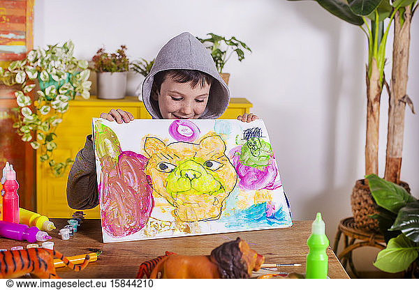 Junge zeigt seine Kunstwerke zu Hause.