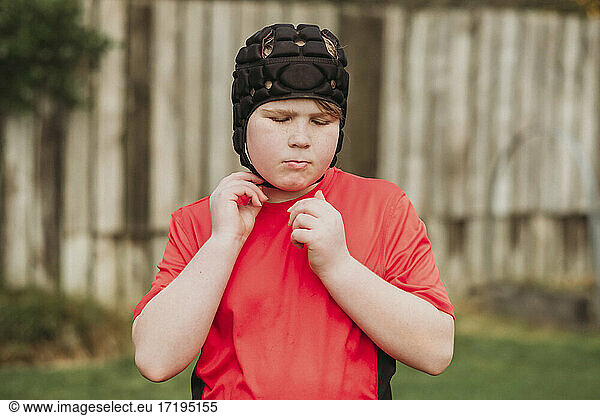 Junge zieht im Hinterhof Rugby-Schutzkleidung an