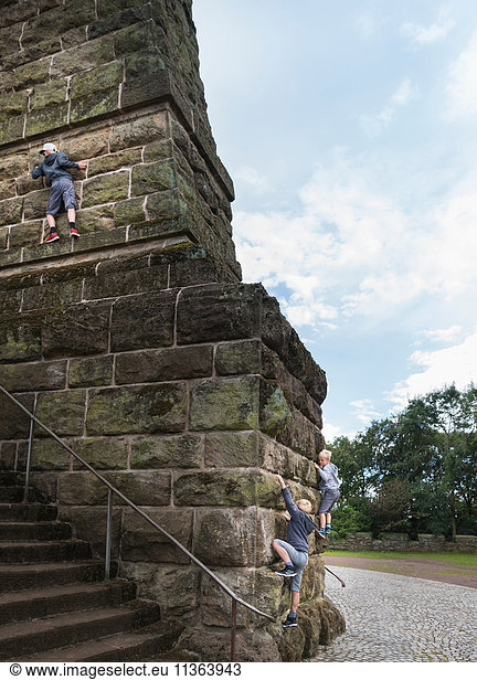 Jungen klettern an Steinwand