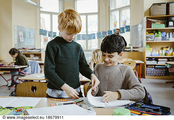 Jungen teilen ein Buch beim Lernen im Klassenzimmer