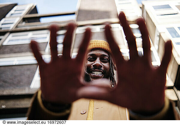 junger Afrikaner  der lächelt und mit den Händen gestikuliert  während er in die Kamera schaut. niedrige Einstellung.