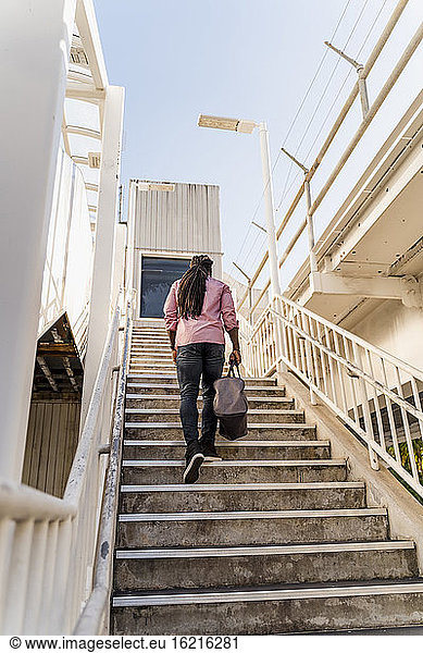 Junger Afroamerikaner mit Tasche auf einer Treppe in Miami  Florida  USA