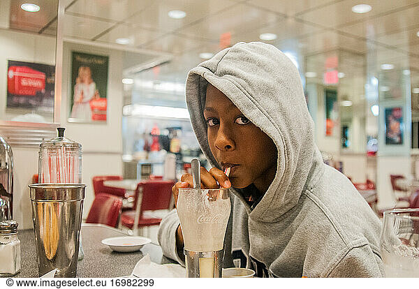 Junger afroamerikanischer Teenager trinkt Milkshake